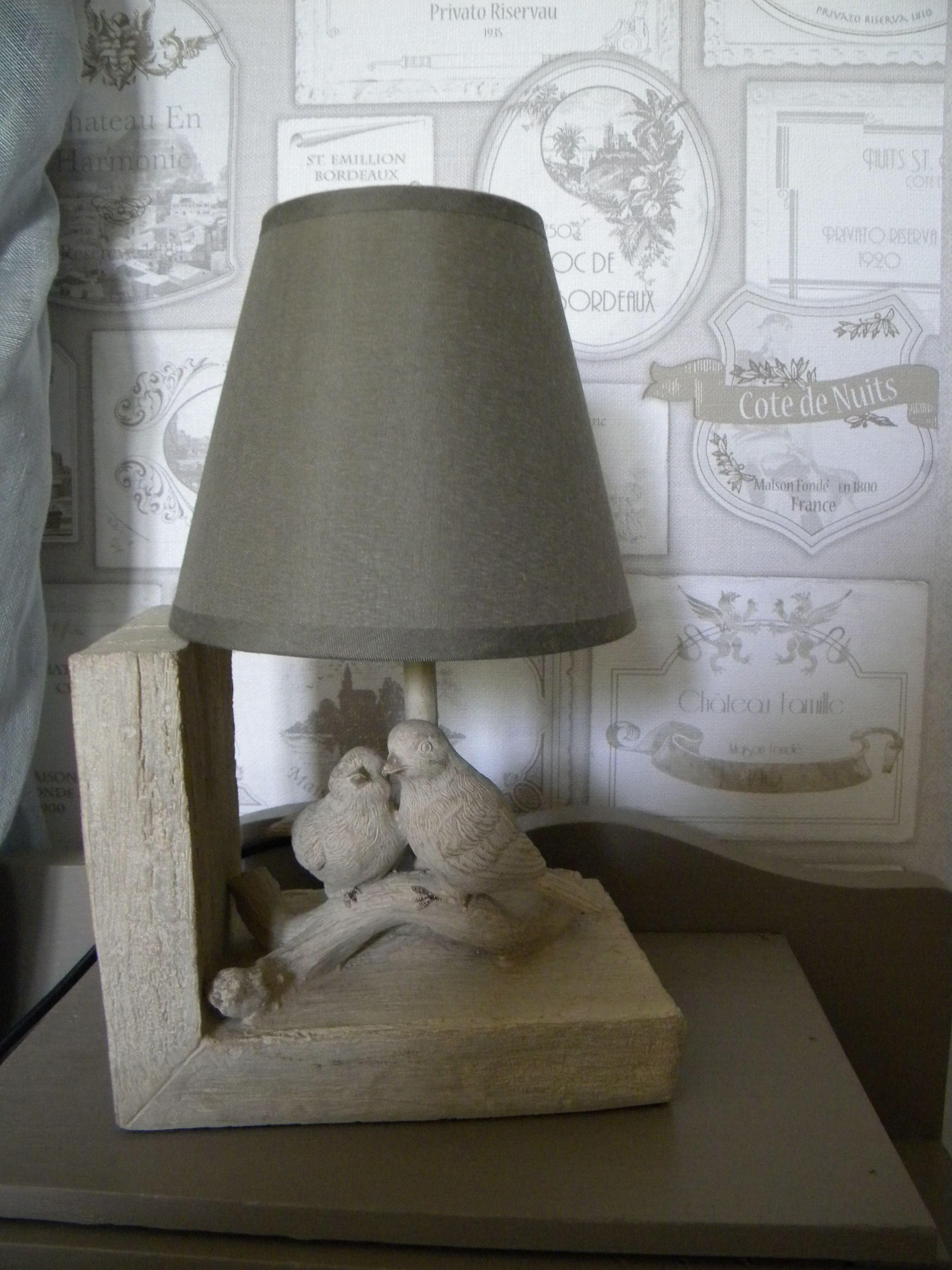 A lamp with a grey shade and a wooden base featuring two birds.