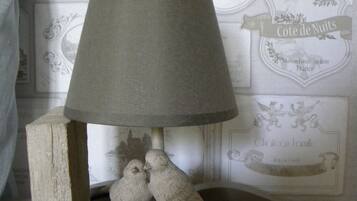A lamp with a grey shade and a wooden base featuring two birds.