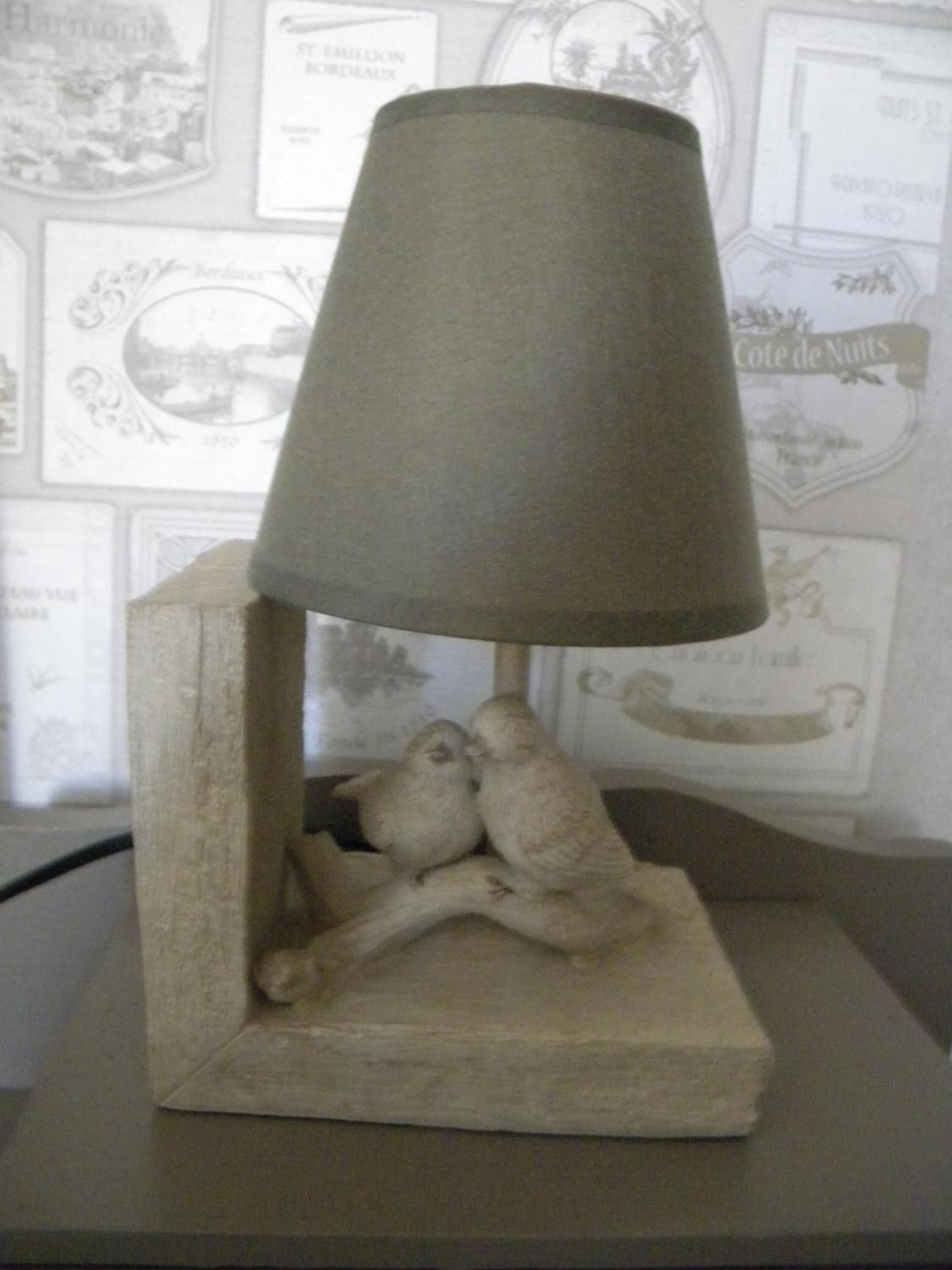 A lamp with a textured shade and a base featuring two birds.