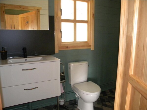 Un baño con lavamanos blanco, inodoro y espejo sobre el lavamanos.