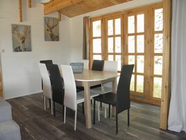 Un comedor con una mesa redonda, cuatro sillas y una cesta azul.