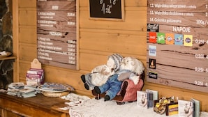 A wooden interior with a menu board, a cozy seating area, and a small display of snacks. - Motel w Lace (Boleslawiec)