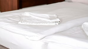 A neatly made bed with white linens, a wooden headboard, a flat-screen TV mounted on the wall, and a small bedside table with a glass and a book. - Motel w Lace (Boleslawiec)