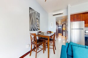 A modern kitchen with stainless steel appliances, a dining area with wooden furniture, and a blue sofa.