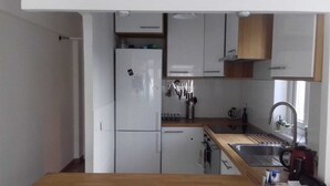 A compact kitchen with white cabinets, a stainless steel sink, and a wooden countertop.