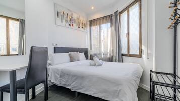 Habitación de hotel con cama, escritorio, silla y ventana con cortinas.