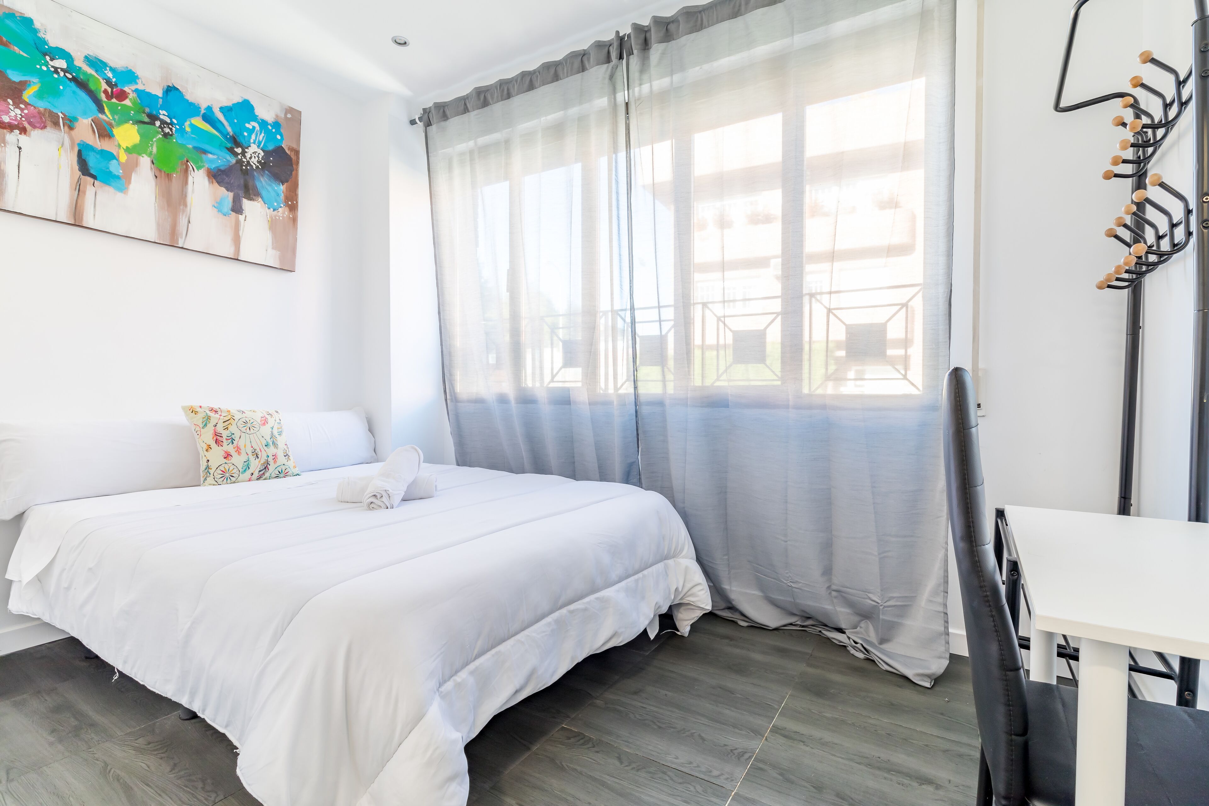 A bedroom with a bed, a desk, and a chair.