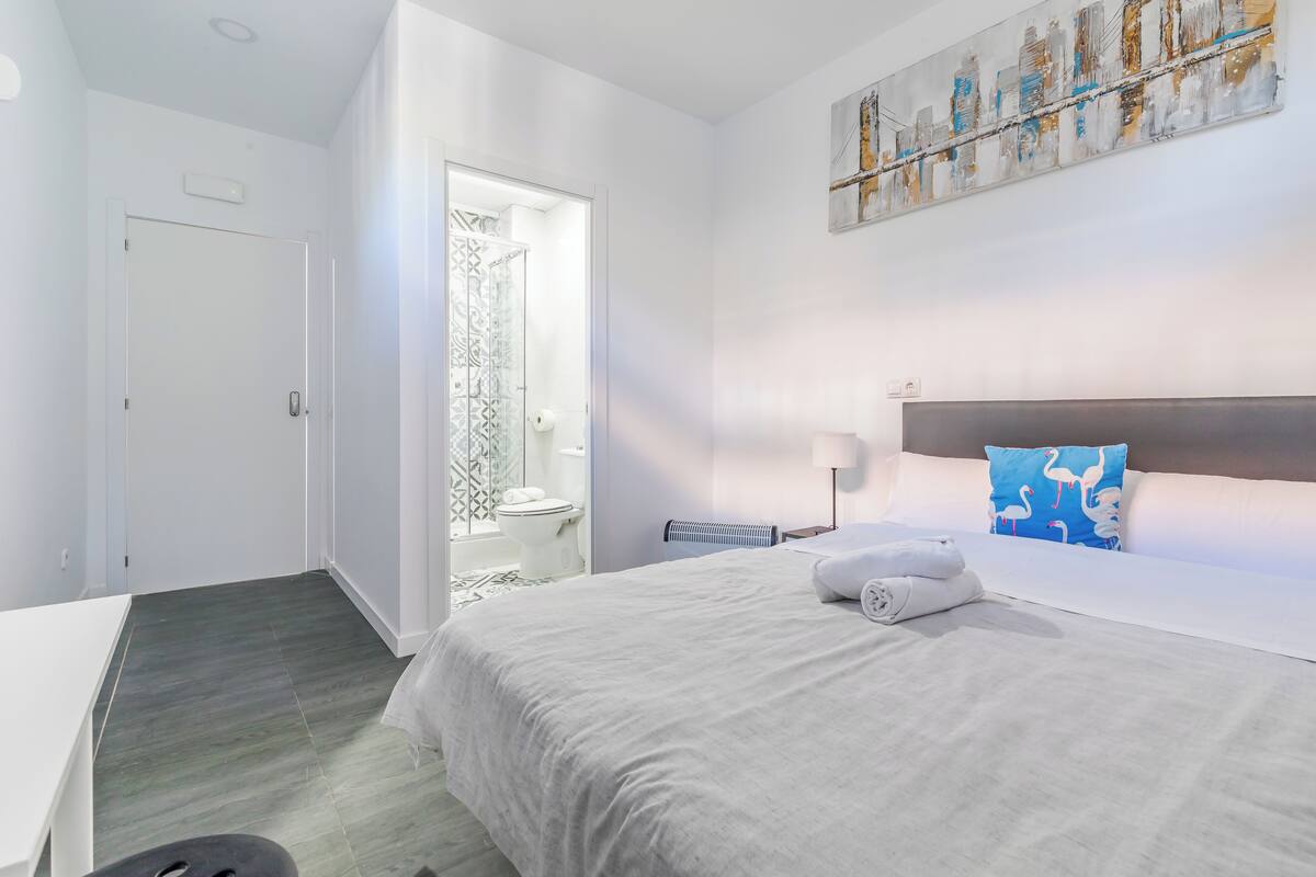 Ein Hotelzimmer mit Bett, Nachttisch, Lampe und einem Gemälde an der Wand.