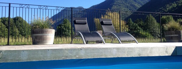 Una piscina al aire libre, sombrillas, sillones reclinables de piscina