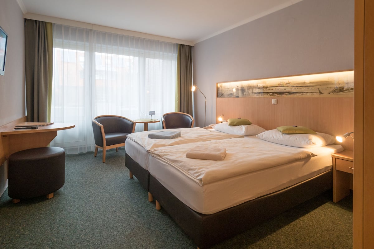 Une chambre d’hôtel avec un grand lit, deux chaises, un bureau et une petite table.