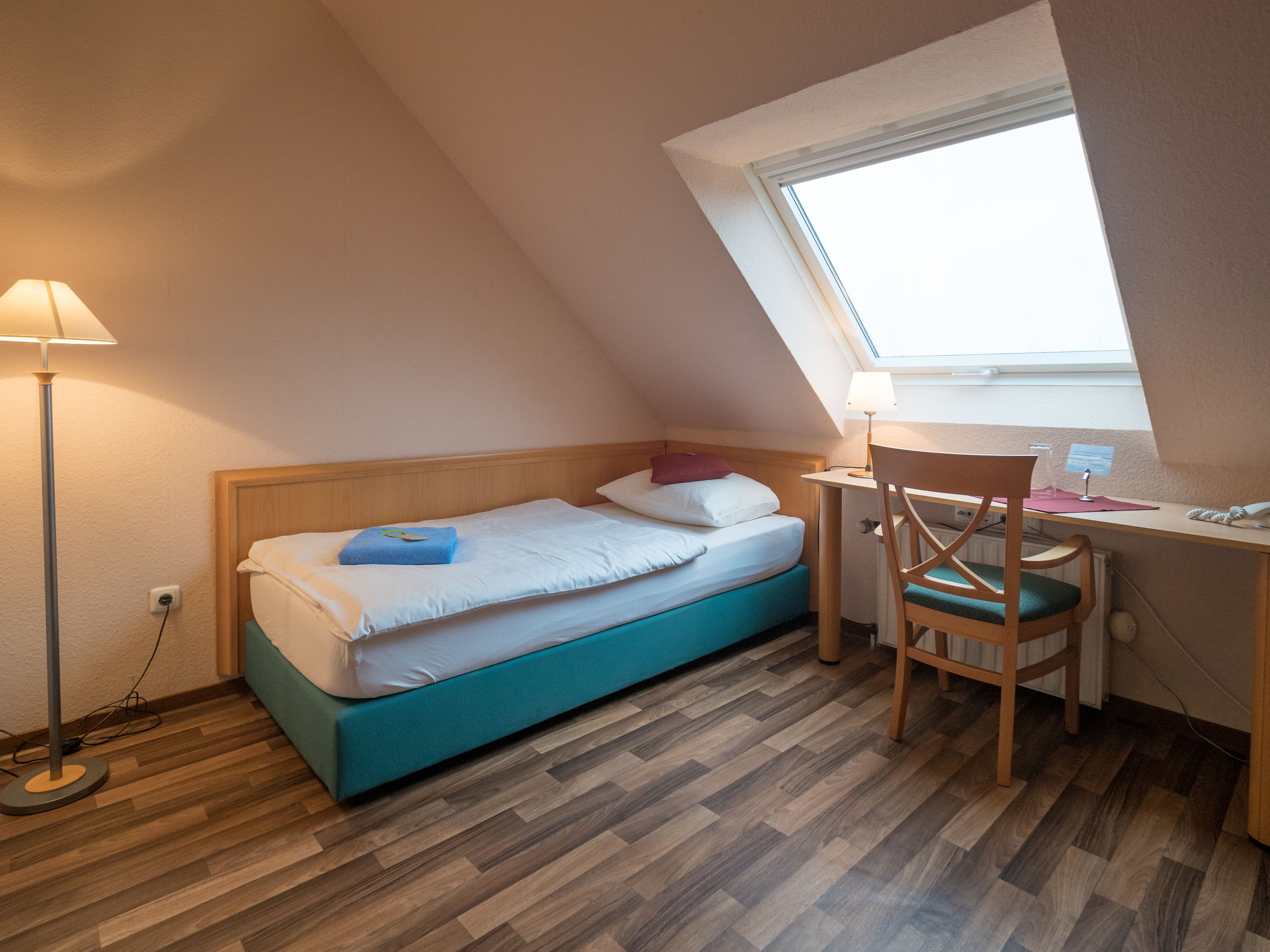Een kleine, knusse kamer met een bed, een bureau en een stoel.