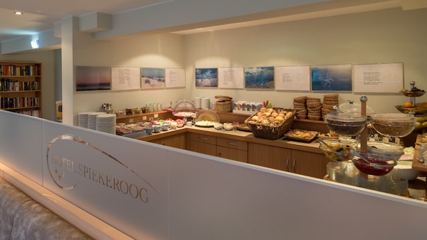 A buffet area with various food items and a bookshelf in the background. - Hotel Spiekeroog (Spiekeroog)