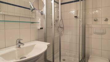 A bathroom with a glass-enclosed shower, a sink, and a toilet.