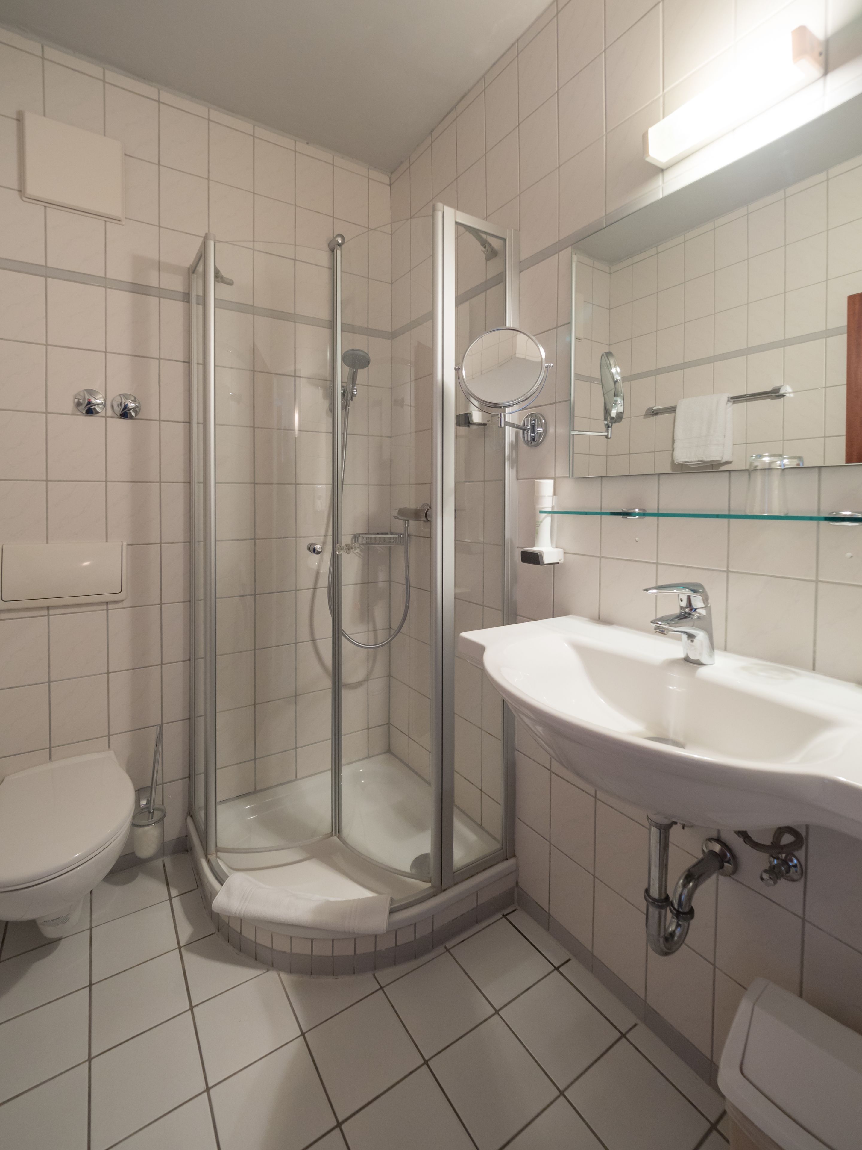A modern bathroom with a glass-enclosed shower, a white sink, and a mirror above the sink.