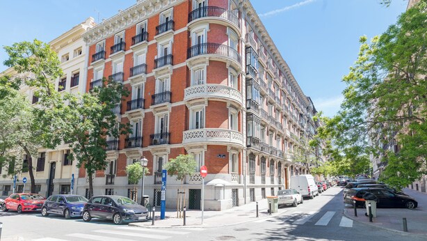Ein mehrstöckiges Gebäude mit klassischer Architektur, mit Balkonen und einem Hauseingang an der Ecke.