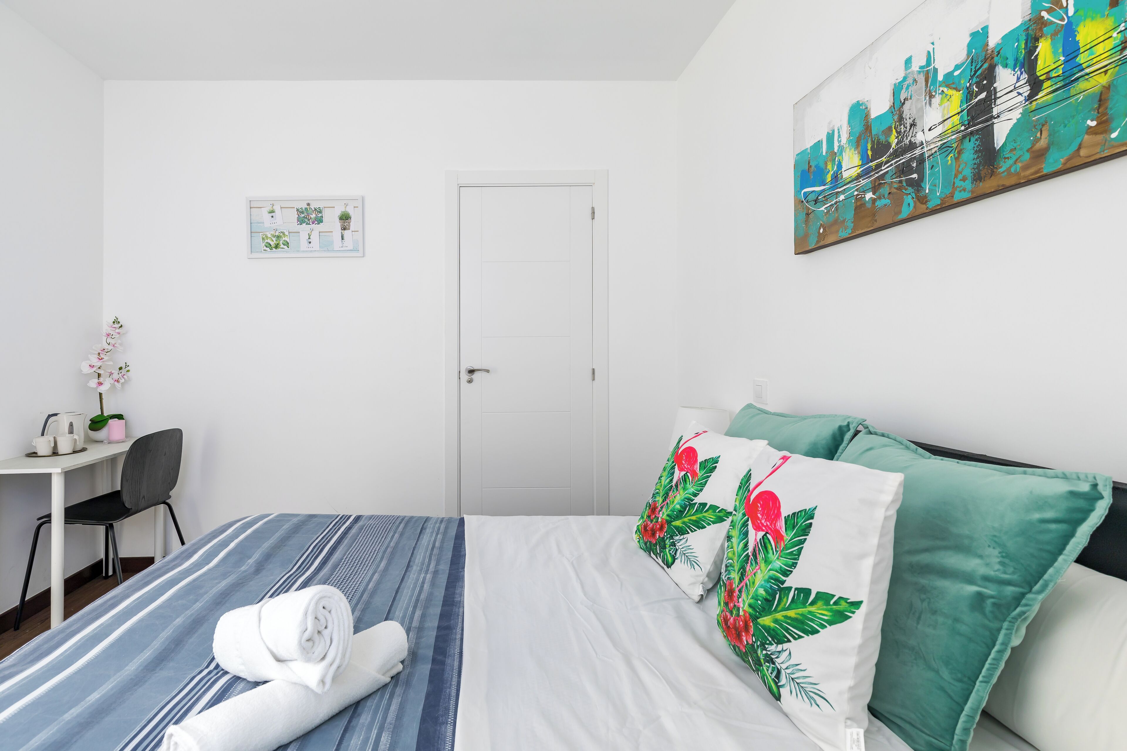 Una habitación de hotel con cama, escritorio, silla y puerta.