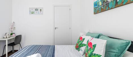 Una habitación de hotel con cama, escritorio, silla y puerta.