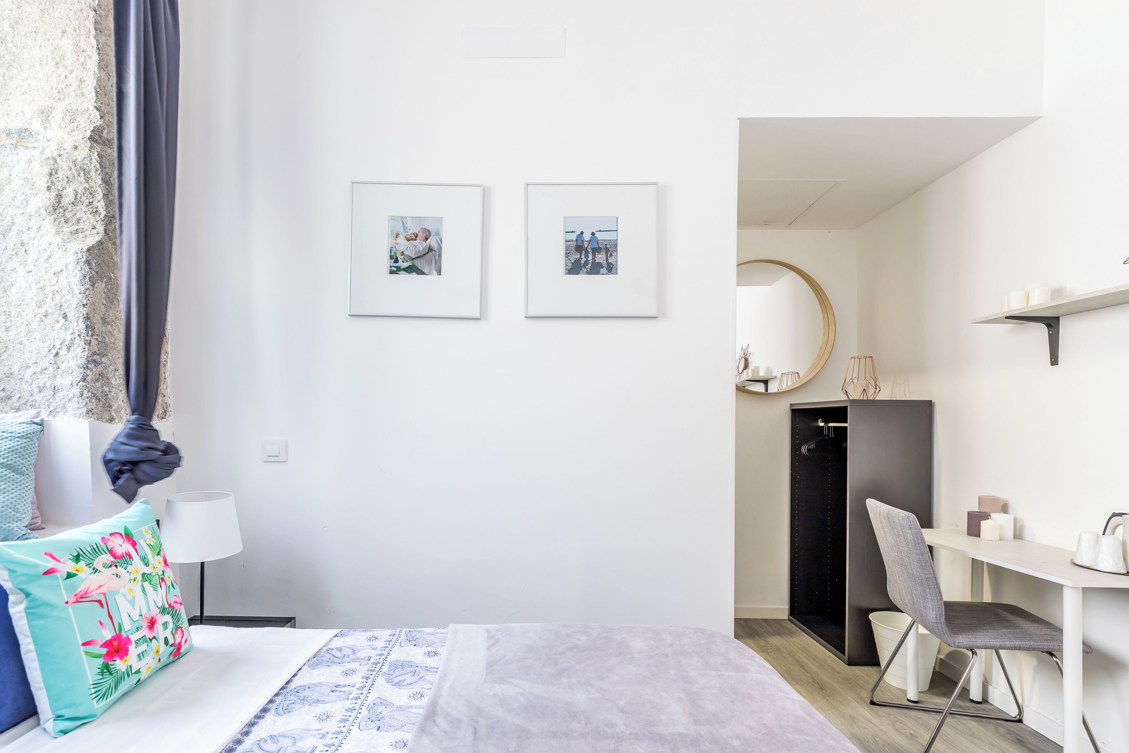 Une chambre à coucher comprenant un lit, un bureau, une chaise, une lampe et deux tableaux encadrés accrochés au mur.