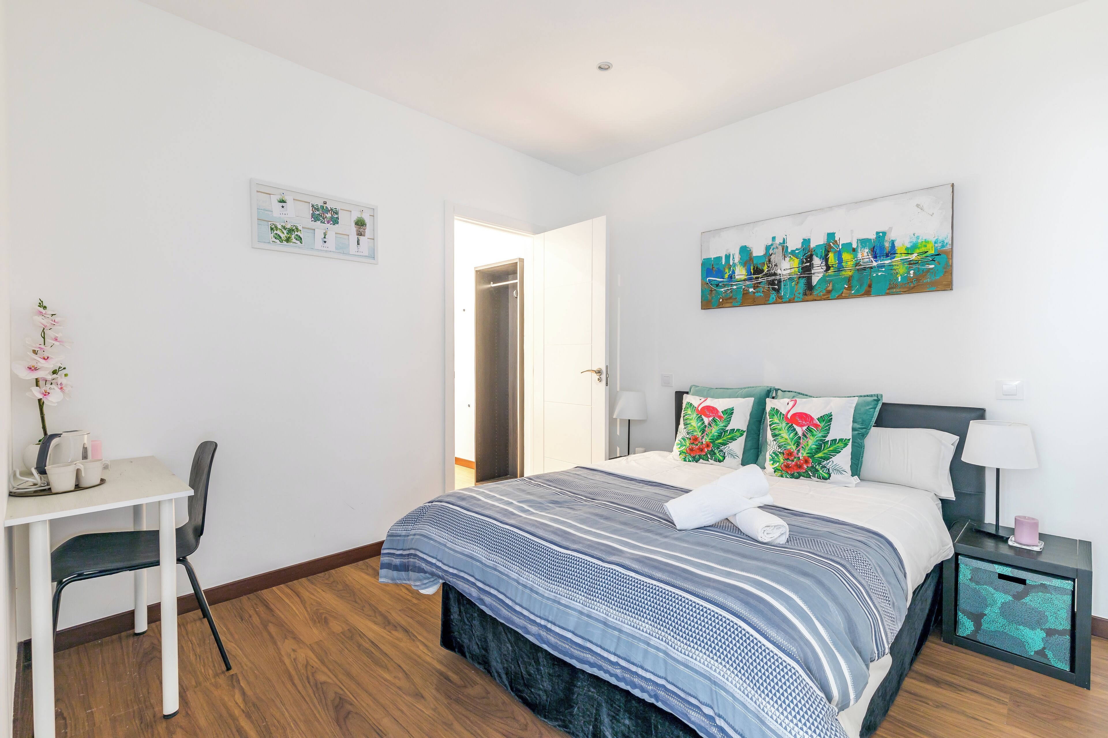 Una camera da letto con un letto, un comodino, una sedia e un quadro appeso al muro.