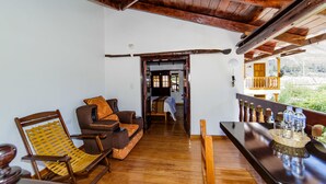 A wooden-floored room with a sofa, a rocking chair, and a bar area with glasses and bottles.