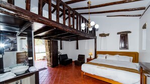 A room with a wooden bed, a large mirror, a stone fireplace, and a red-tiled floor.