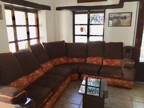 Una sala de estar con un sofá seccional en forma de L, una mesita de centro y un ventanal con vistas al exterior.