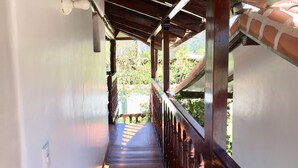 A wooden staircase with a metal railing leading to a covered area with a brick wall.