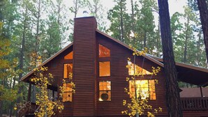 A wooden cabin with a chimney, large windows, and a porch. - Luxury Cabin Retreat with Hot Tub on Spacious Wooded Lot (Pinetop)