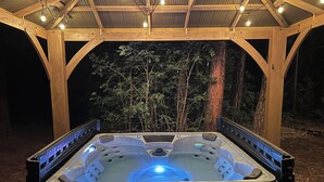 A hot tub under a wooden pavilion with a metal roof, surrounded by trees. - Luxury Cabin Retreat with Hot Tub on Spacious Wooded Lot (Pinetop)
