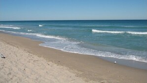 Ein sandiger Strand mit sanften Wellen und blauem Himmel.