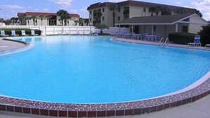 Ein Schwimmbecken mit Liegestühlen und einem Gebäude im Hintergrund.
