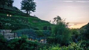 A lush garden with a stone pathway, a weeping willow, and a sunset in the background. - Il Bottaccio, Relais & Chateaux (Montignoso)