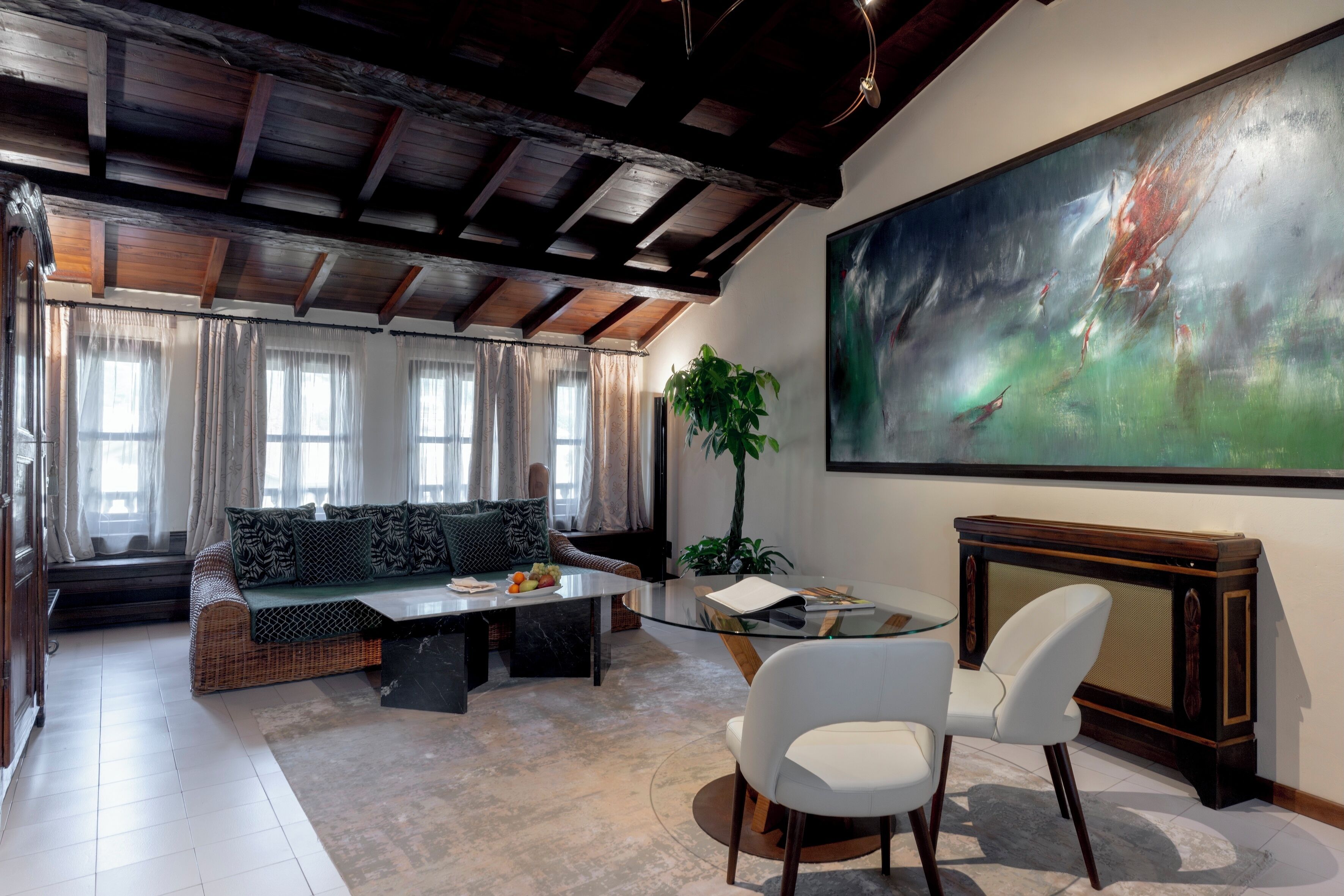 A modern living room with a high ceiling, a large abstract painting, a sofa, a coffee table, and a television.