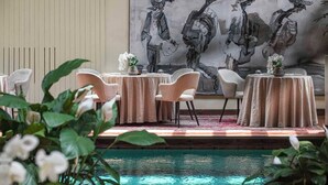 A dining area with round tables, chairs, and a large abstract painting on the wall. - Il Bottaccio, Relais & Chateaux (Montignoso)