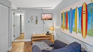 En moderne stue med en grå sofa, et træbord og et tv ophængt på væggen.