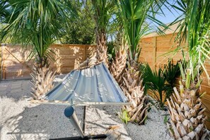 Eine Hängematte in einem Garten mit Palmen und einem Holzzaun.