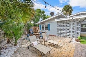 A patio with lounge chairs, a barbecue grill, and a white fence with lattice design. - Heated Pool, Mini Golf, Walk to Beach, Beach Gear (St Augustine)