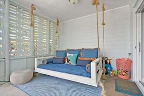 A white swing bed with blue bedding, a woven basket, and a blue patterned rug. - Heated Pool, Mini Golf, Walk to Beach, Beach Gear (St Augustine)