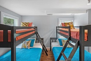 A room with two bunk beds, each with a blue bedspread and orange pillows, and a window with blinds. - Heated Pool, Mini Golf, Walk to Beach, Beach Gear (St Augustine)