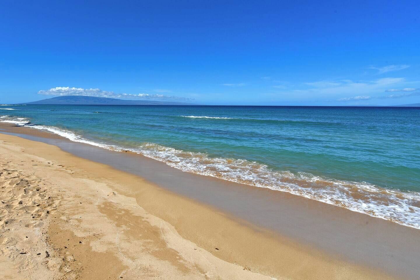 A beach with clear blue water and a sandy shore.