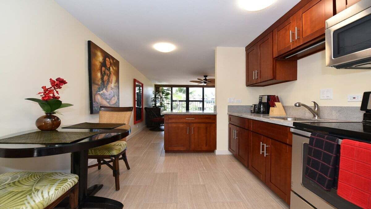 A modern kitchen with wooden cabinets, a microwave, and a dining area with a table and chairs.