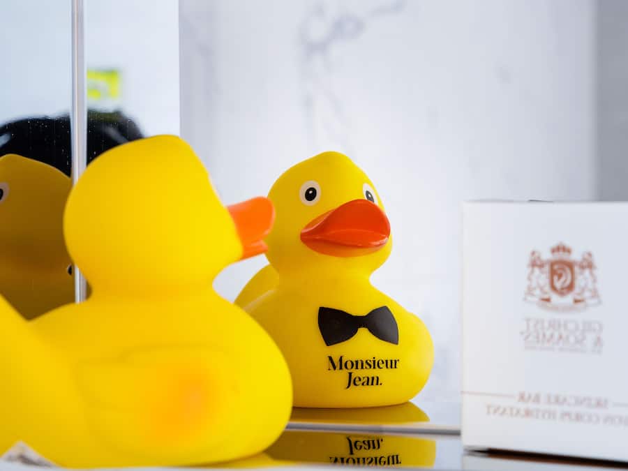 Two yellow rubber ducks with black bow ties and a white envelope with a crest.