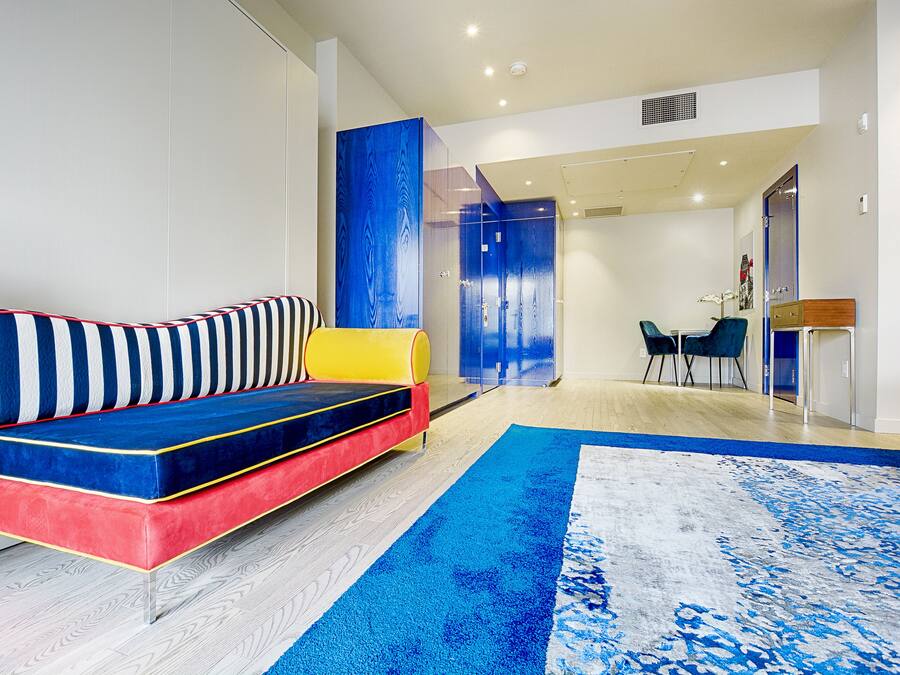 Una sala de estar moderna con un sofá de colores, una pared de acento azul y una alfombra grande.