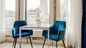 A modern room with two blue velvet chairs, a glass table, and a view of a cityscape through large windows. - Monsieur Jean, Vieux Québec (Québec City)