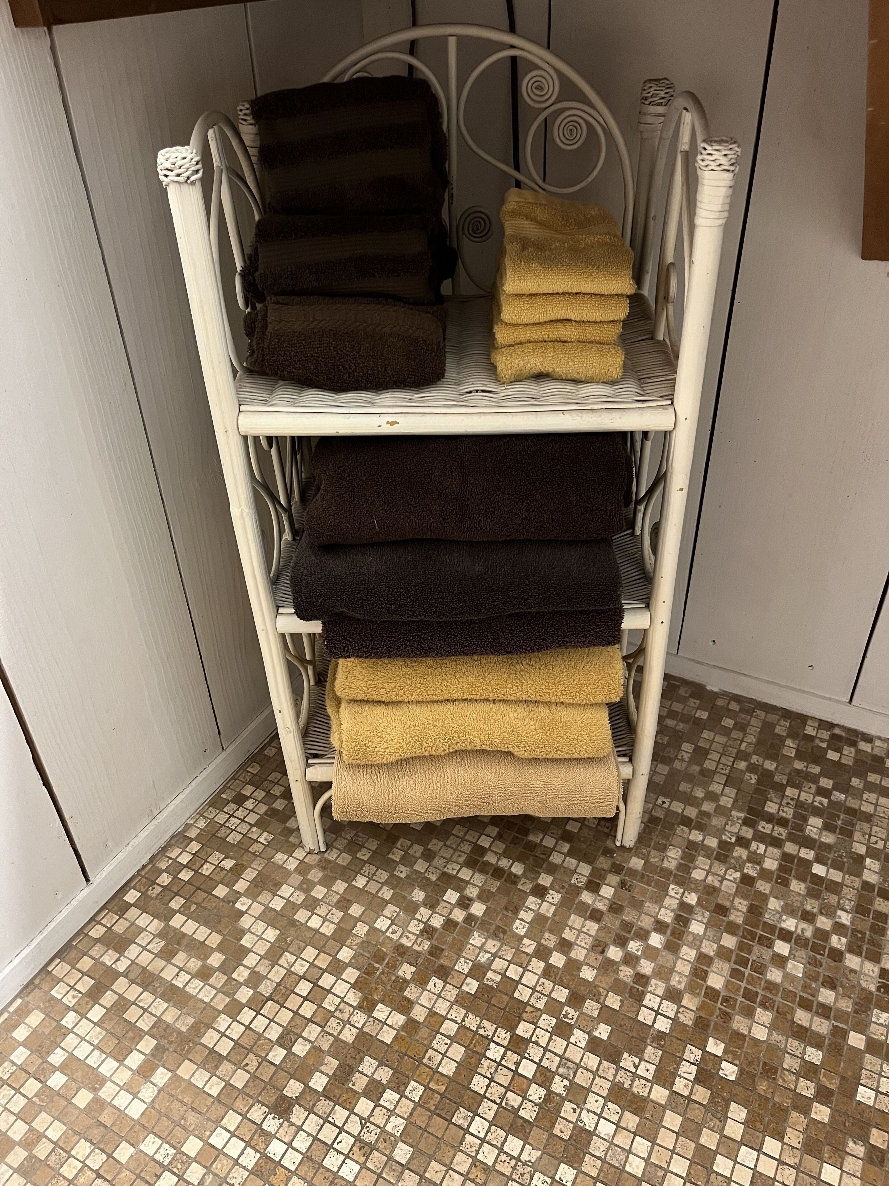 A metal shelf with folded towels in various colors.