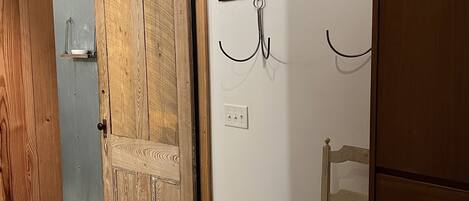 A room with a wooden door, a chair, a small table, and a wall-mounted hook.