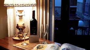 A room with a table set for two, featuring a wine bottle, two wine glasses, and a menu. - Isolabella B&B (Mazara del Vallo)