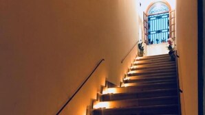 A staircase with illuminated handrails and steps, leading to a door with a decorative archway. - Isolabella B&B (Mazara del Vallo)
