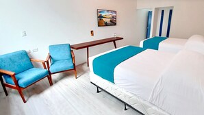 Una habitación de hotel con dos camas, un escritorio y dos sillas azules.