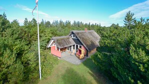 A thatched-roof house with a patio and a flagpole. - Child-friendly thatched cottage on a large plot. Natural property from private owner (Fereininsel Römö)